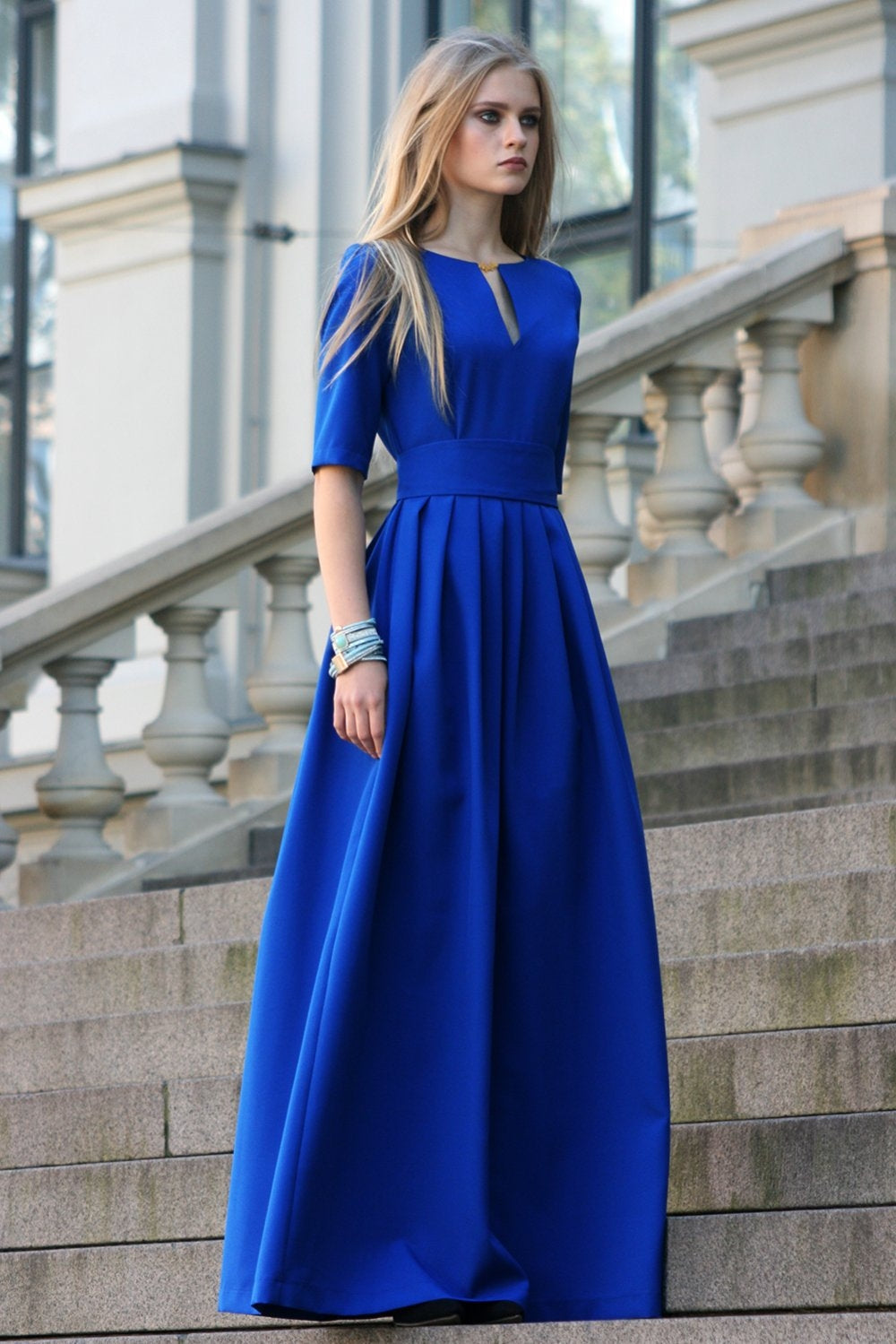 Blue long dress with pleats. Golden color detail in neckline
