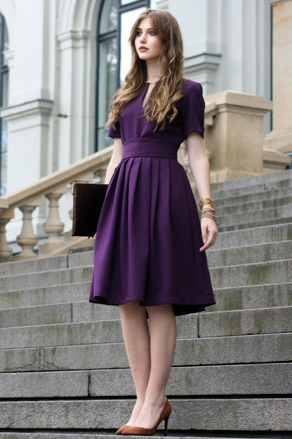Volles lila Kleid mit Falten. Golddetail am Ausschnitt