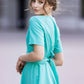 Turquoise dress with circle skirts. Golden color detail in neckline
