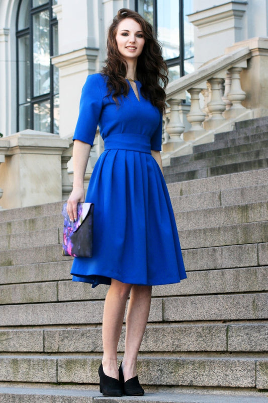 Blue dress with pleats. Golden color detail in neckline