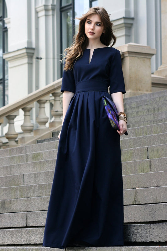Long dark blue dress with pleats. Golden color detail in neckline