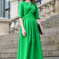 Green maxi dress with pleats. Golden color detail in neckline